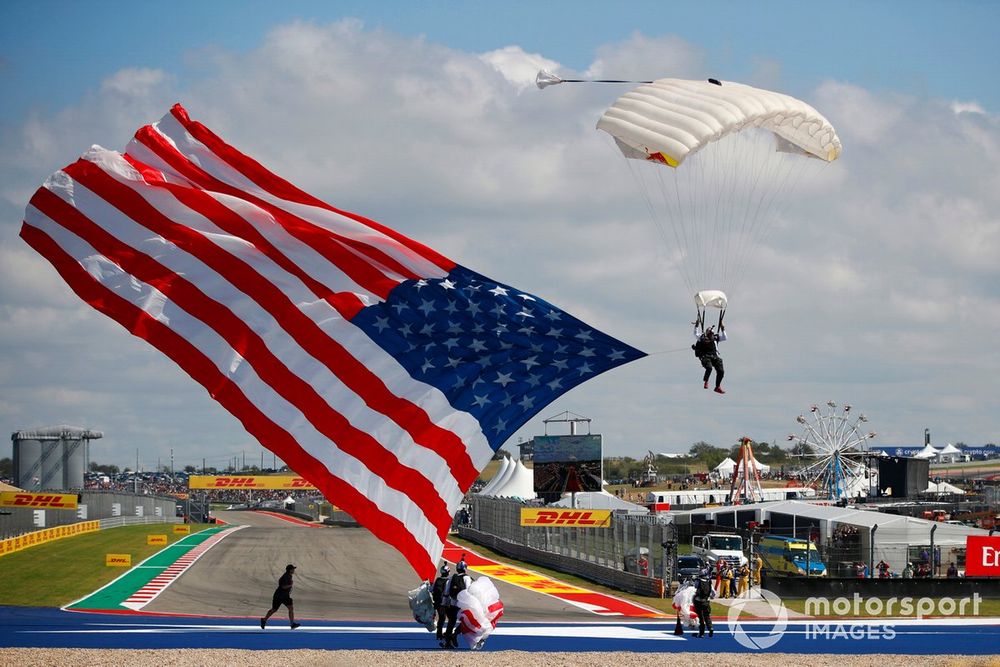 A parachutist arrives with a US flag at the US GP